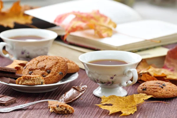 Herbstlicher Lebensstil mit heißem Tee, Süßigkeiten und gelben Blättern — Stockfoto