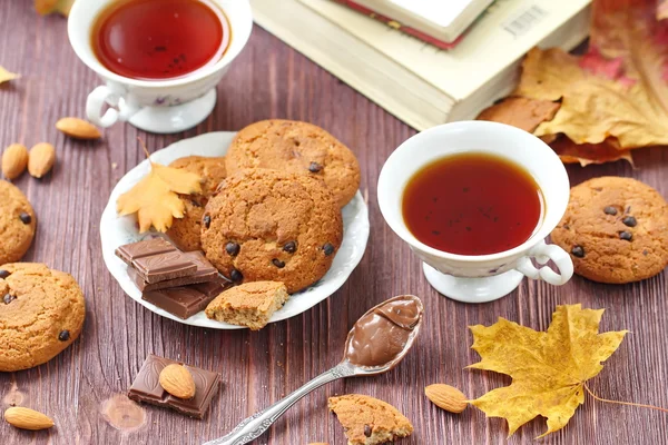 Estilo de vida otoñal con té caliente, dulces y hojas amarillas — Foto de Stock