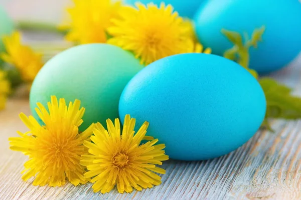 Huevos de Pascua y flores sobre fondo de madera — Foto de Stock