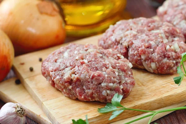 Raw cutlets on a chopping board and ingredients — Stock Photo, Image