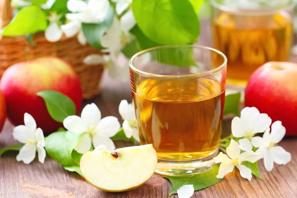 Sladký jablečný mošt, jablka a květiny na stole — Stock fotografie