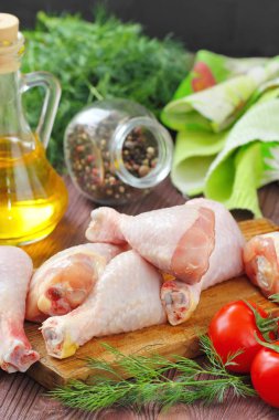 Baharatlar ve sebzeler bir kesme tahtası üzerinde çiğ tavuk budu