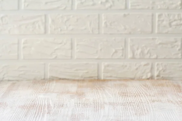 Witte houten tafel met een bakstenen muur als achtergrond — Stockfoto