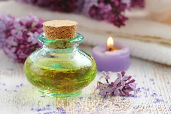 SPA setting. Essential aroma oil with lilac on wooden background