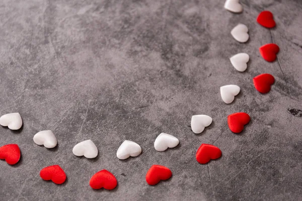 little red and white hearts on a black stone background. Valenti