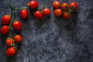 Taze kiraz domatesleri koyu taş arka planda ve kopyaları var.