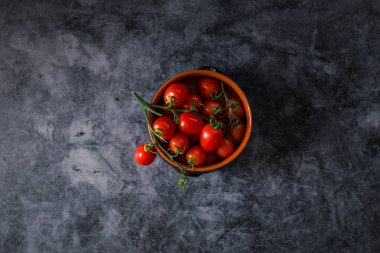 Taze kiraz domatesleri koyu taş arka planda ve kopyaları var.