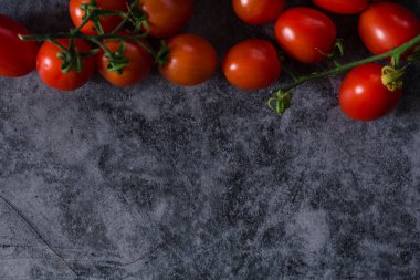 Taze kiraz domatesleri koyu taş arka planda ve kopyaları var.