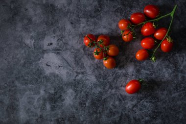 Taze kiraz domatesleri koyu taş arka planda ve kopyaları var.
