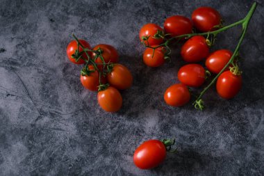 Taze kiraz domatesleri koyu taş arka planda ve kopyaları var.
