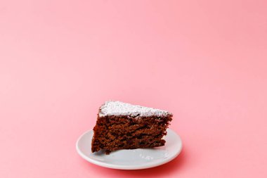 Beyaz tabakta, pembe arka planda çikolatalı kek.
