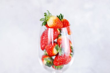 Açık gri b 'de şeffaf cam dolusu taze kırmızı çilek.