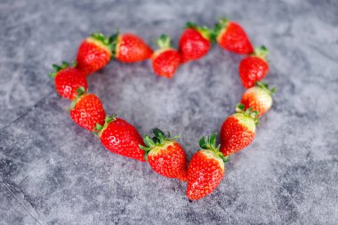 Koyu arka planda bir sürü taze kırmızı çilek. Sağlıklı kırmızı rıhtım