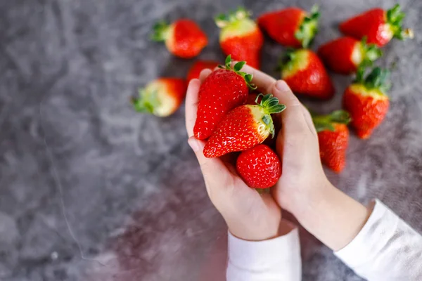 Barn som håller färska röda jordgubbar i händerna — Stockfoto
