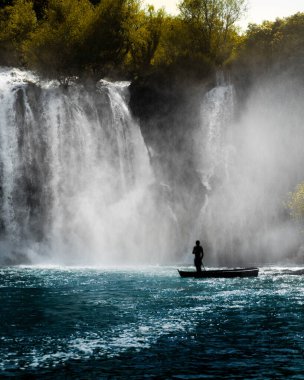 Bosna-Hersek 'te tekne ve görkemli Kravice şelalesinde duran kişinin silueti
