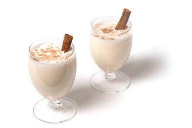 Şeffaf bir şarap kadehinde noel kokteyli, tarçın çubuğuyla süslenmiş, rendelenmiş hindistan cevizi serpiştirilmiş. Beyaz arka planda izole edilmiş. Boşluğu kopyala.