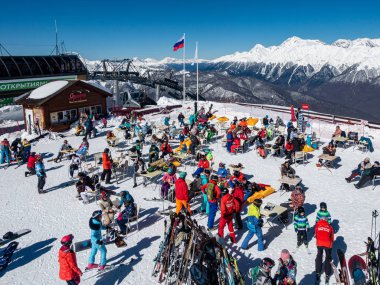 Rosa Khutor, Sochi / Rusya - Mart 06 2018: Kayakçılar ve snowboardcular güneşlenirken dinleniyorlar. Yükseklik deniz seviyesinden 2200 metre..