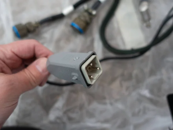 Bir adam elinde nadir bulunan metal kare kablo bağlayıcısını tutuyor. Dof sahasının derinliği çok sığ. Bulanık arkaplan.