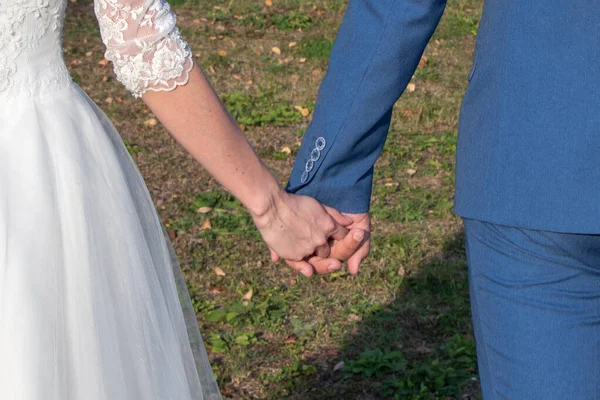 Gelin ve damat el ele tutuşarak çimlerde yürüyor..