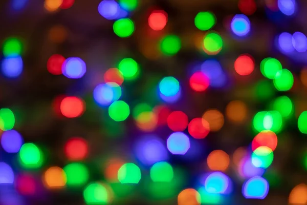 Glowing and festive colored light spots. In camera and lens bokeh. Christmas fairy LED lights defocused giving a blurred effect. Background for design.