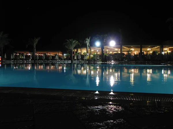 Modern güney otelinde gece yüzme havuzu sahnesi.