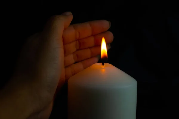 Mão protegendo a luz da vela do vento na escuridão — Fotografia de Stock