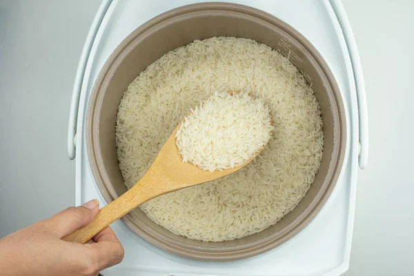 Cuchara de madera en el arroz y la olla eléctrica de arroz — Foto de Stock