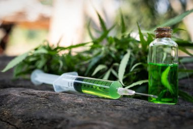 Syringe there is medicine inside on table wood at cannabis backg