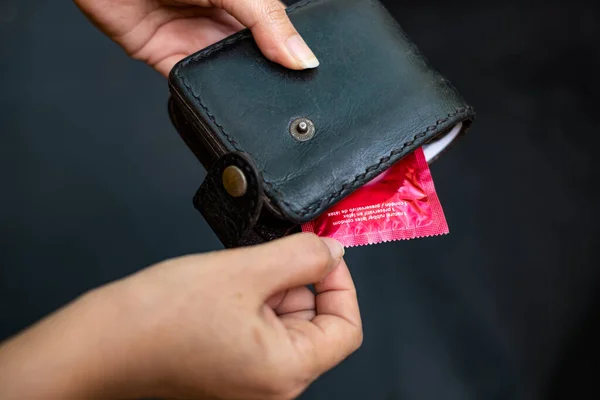 Närbild kvinna hand håller svart läder plånbok med en röd lägenhet — Stockfoto