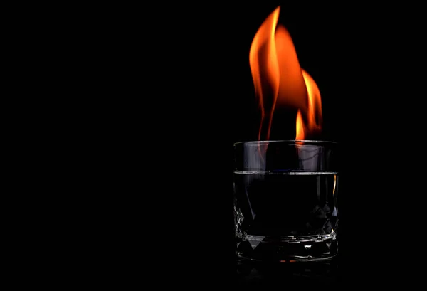 Glass with vodca and fire flame on black background — Stock Photo, Image