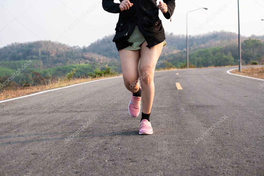 Photo fone view Asia young smiling woman runner running on asphalt road, female in sport cloth and wear a hat jogging, Healthy lifestyle concept