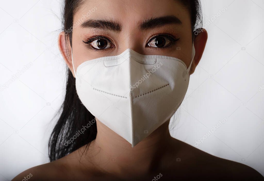 Close up of a woman putting on a respirator N95 mask to protect from airborne respiratory diseases as the flu covid-19 coronavirus ebola PM2.5 dust and smog, Safety virus infection concept
