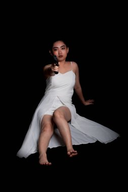 Güzel bir Asyalı kadının portresi bir eli siyah arka planda, genç, uzun saçlı seksi bir kız güzel kadınlar tabancayla ayakta duruyor, kameraya bak.