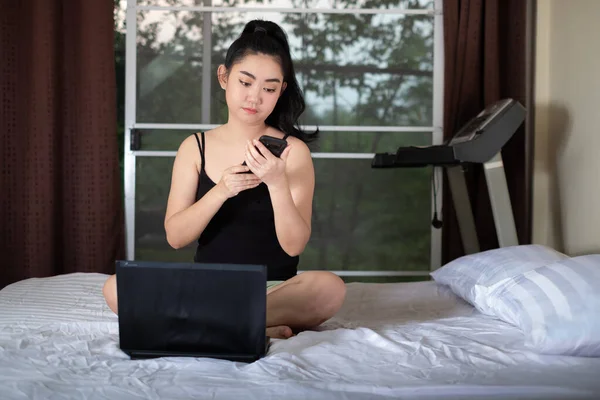 Portrait Asia woman sitting on the and bed using laptop works in the bedroom at home, works at home or work from own homes concept