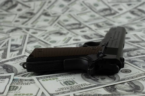 Black gun pistol on stack money 100 dollars background