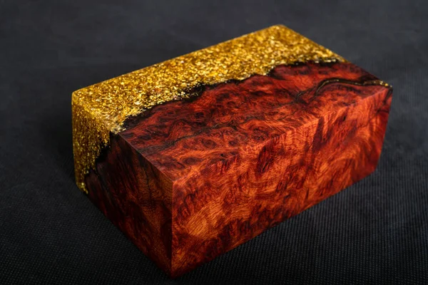 Casting epoxy resin gold with nature burl BURMA PADAUK wood cube on black background