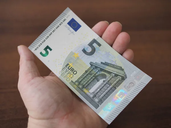 На человеческой руке лежит красивая новая купюра 5 евро. Крупный план, размытие — стоковое фото