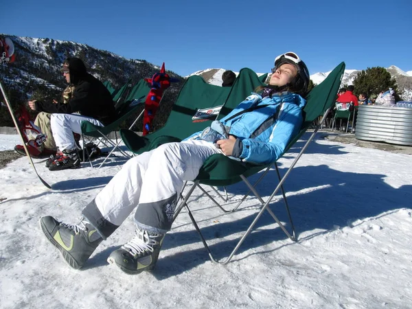 Snowboardisté a lyžaři relaxují a opalují se pod jasnými paprsky slunce v lyžařském středisku ležícím na lehátkách. Andorra, Andorra La Vella-December, 2011 — Stock fotografie