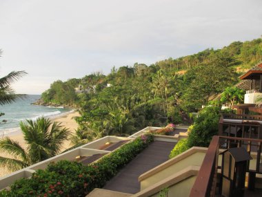 Okyanustaki otelin balkonundan güzel bir manzara, palmiye ağaçları ve plaj. Lüks tatil köyü.