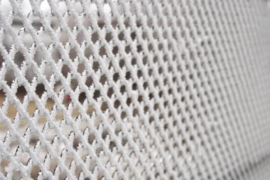 Yakın çekimde, hücrelerde kalın bir kar tabakasıyla kaplı metal ağ.