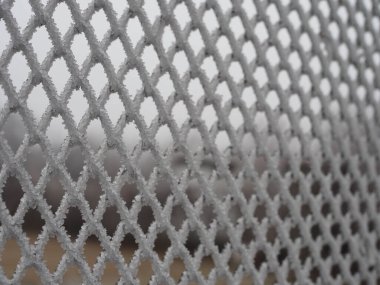 Yakın çekimde, hücrelerde kalın bir kar tabakasıyla kaplı metal ağ.