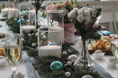 Noel yemeği, Noel sofrası süsü, yanan bir mum, masada mandalinalar, bardaklı ziyafet masası ve aperatifler, ziyafet, masada süsleme kırmızı geyik, güzel