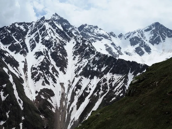 Hermosa vista de la nieve que se derrite montañas Cheget en verano en tiempo soleado. — Foto de Stock