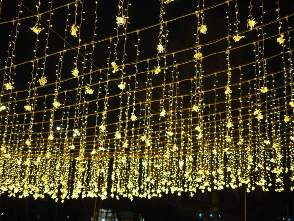 Золотой дождь рождественских украшений, свисающих с неба, на новогодние и рождественские уличные украшения — стоковое фото
