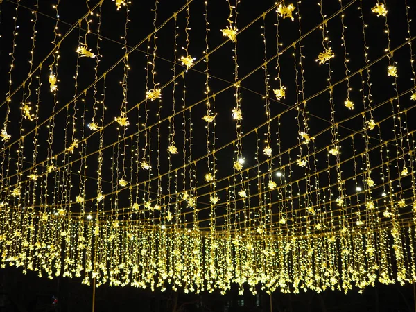 Золотой дождь рождественских украшений, свисающих с неба, на новогодние и рождественские уличные украшения . — стоковое фото