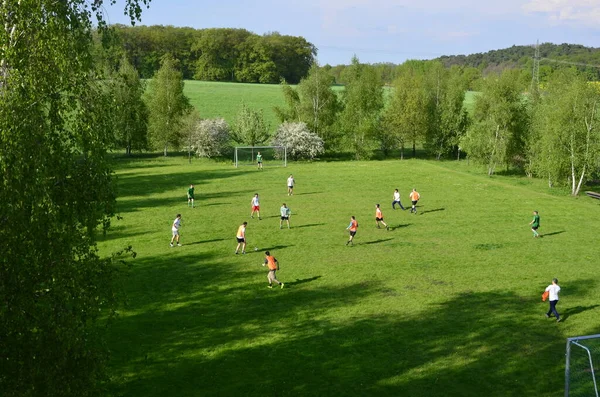 Potsdam, Alemanha - 08 de maio de 2013: Amigos brincalhões correndo e chutando bola no parque. Amigos felizes a passar tempo juntos. A jogar futebol juntos. Conceito de lazer — Fotografia de Stock