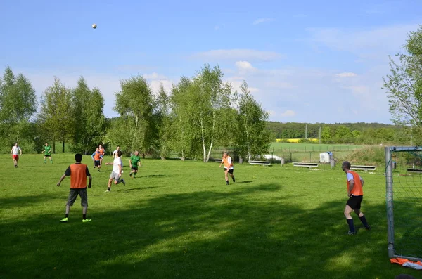 Poczdam, Niemcy - 08 maja 2013: Rozrywani przyjaciele biegają i kopią piłkę w parku. Szczęśliwi przyjaciele spędzają razem czas. Gramy razem w futbol. Koncepcja czasu wolnego — Zdjęcie stockowe