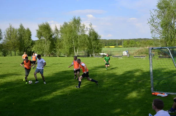 Poczdam, Niemcy - 08 maja 2013: Rozrywani przyjaciele biegają i kopią piłkę w parku. Szczęśliwi przyjaciele spędzają razem czas. Gramy razem w futbol. Koncepcja czasu wolnego — Zdjęcie stockowe