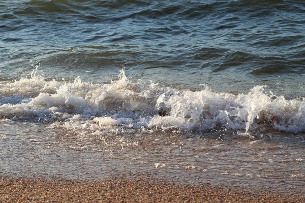 Spatten golven op het strand van de kust bij zonsondergang — Stockfoto