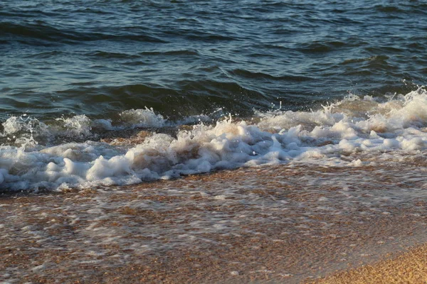 Бризки хвиль на пляжі морського узбережжя на заході сонця — стокове фото